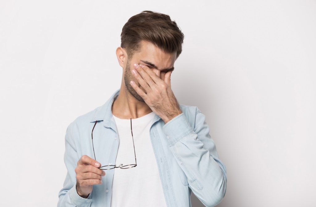 Man holding both of his eyes in pain because he is suffering from dry eye syndrome