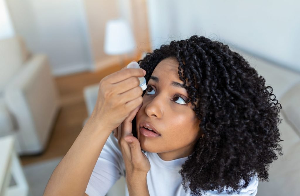 A young woman putting drops into her eyes