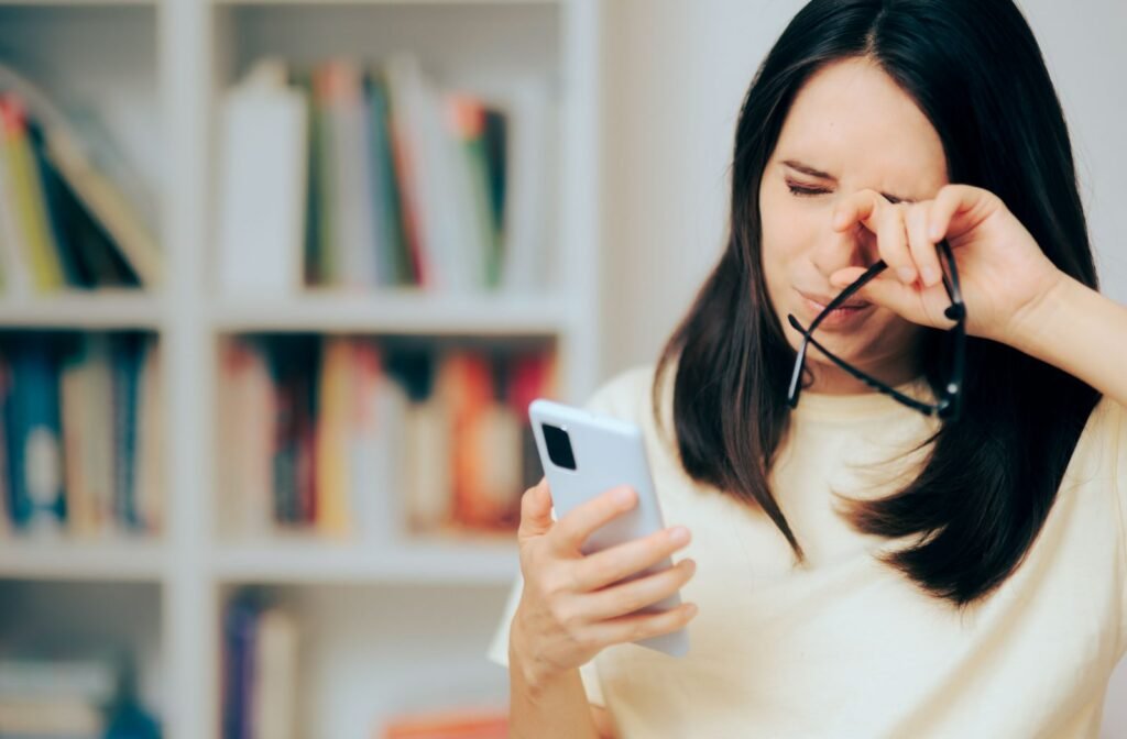 A woman taking off her glasses and rubbing the corner of her eye due to eye strain