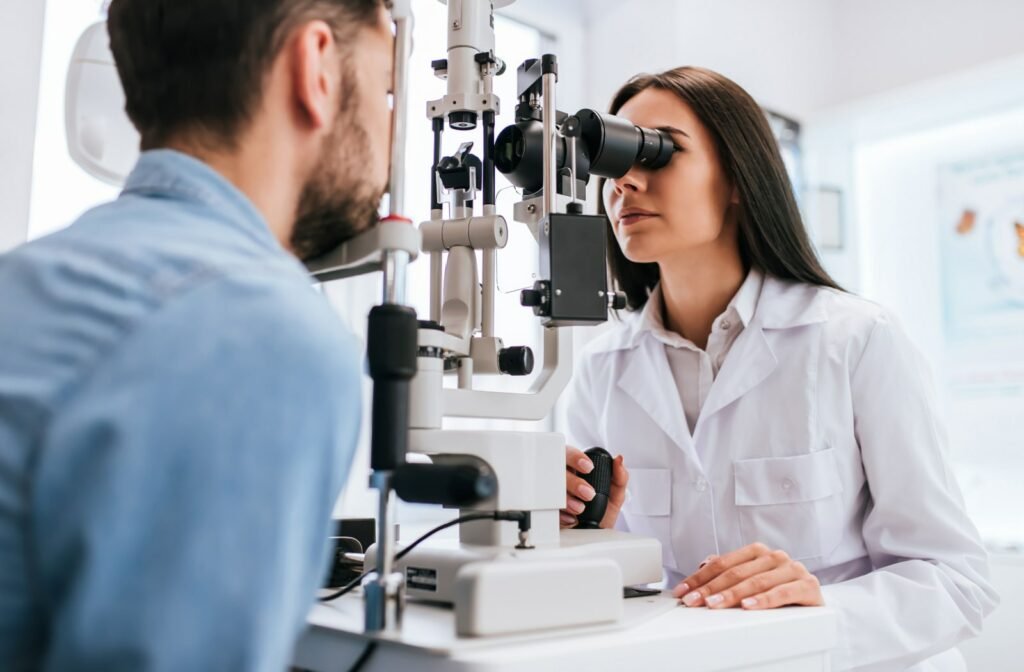 A female optometrist is using a slit lamp to examine a male patient's eyes